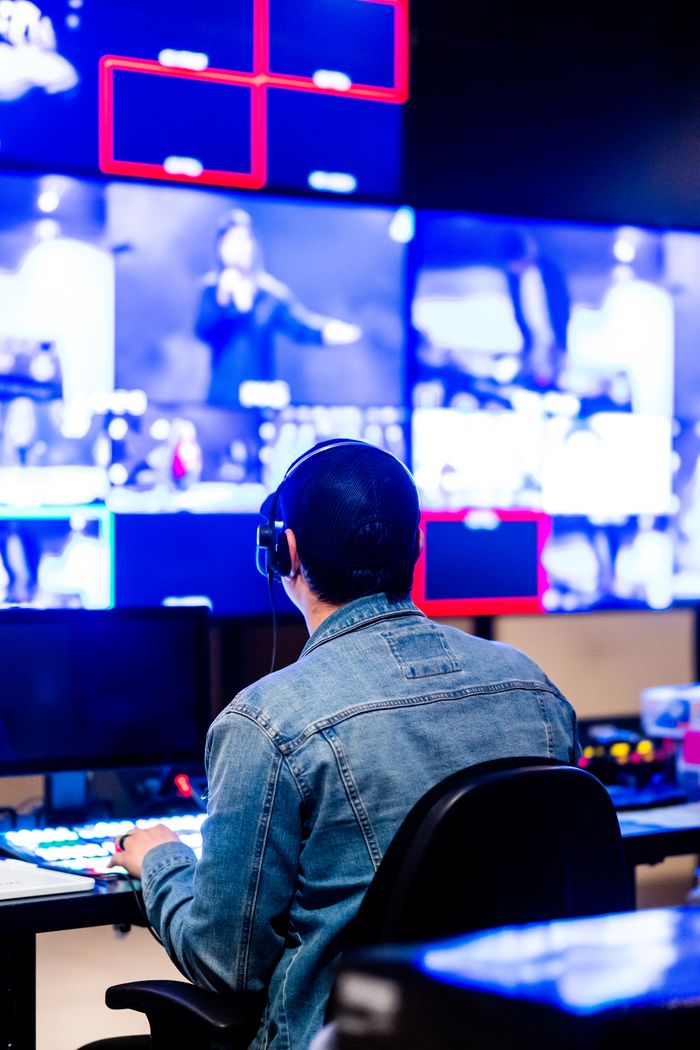 Home Man in a denim jacket working in a modern studio with multiple screens displaying images.