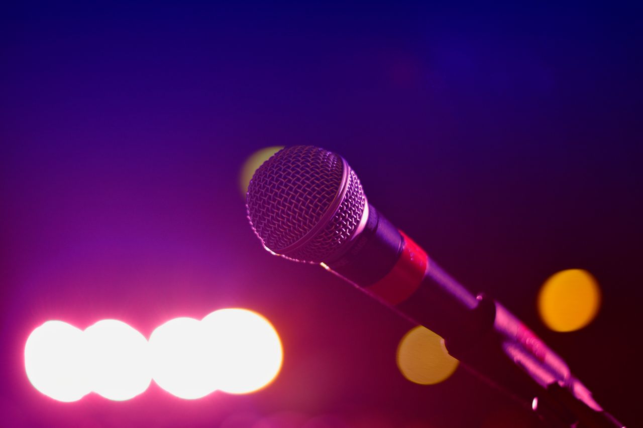 About Colorful stage lighting highlights a microphone in a close-up view, perfect for music and performance themes.